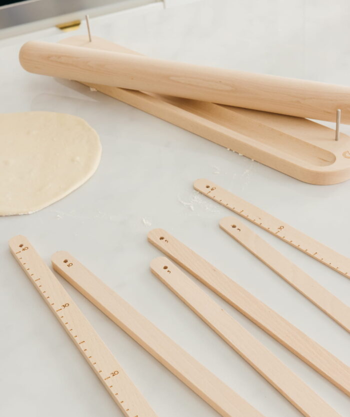 Les 6 règles d'épaisseur graduées du Le Perfecteur de Pâte de Casavida à côté d'une pâte étalée
