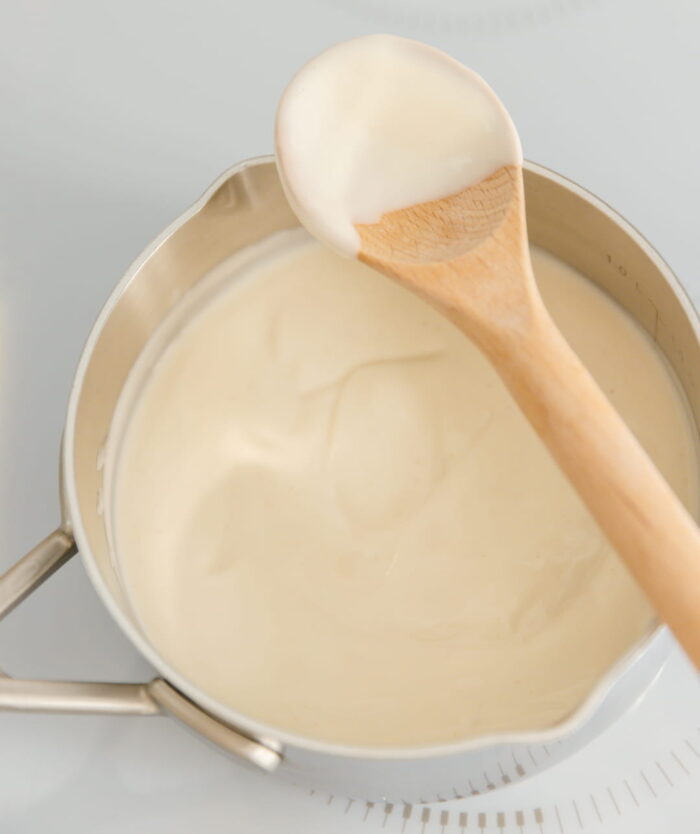 La Cuillère Fétiche de Casavida dans une casserole de sauce béchamel, cuillère de cuisine en bois