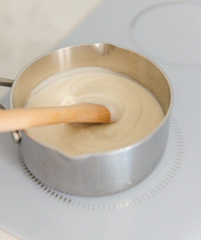 La Cuillère Fétiche de Casavida posée dans une casserole de crème, cuillère de cuisine en bois de hêtre