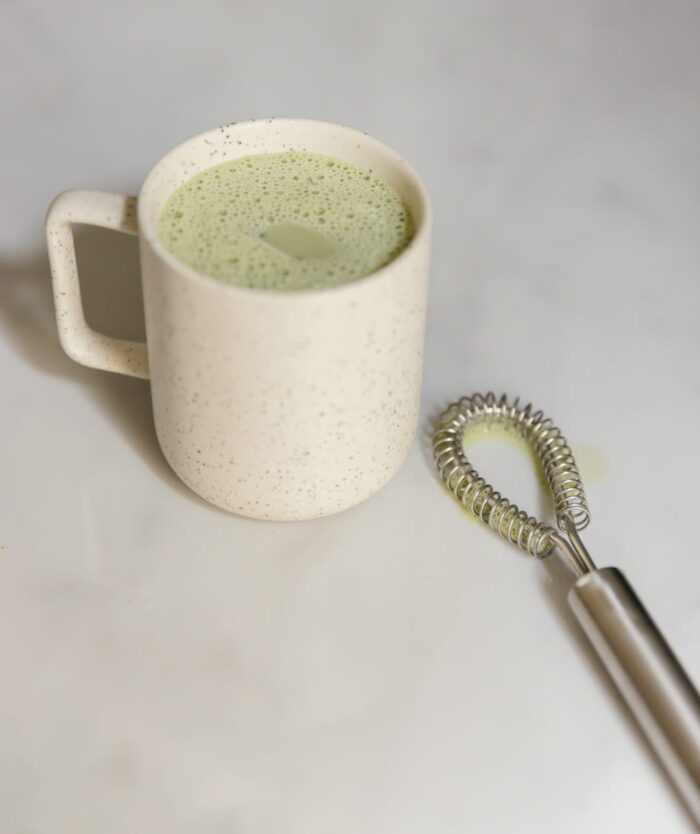 Tasse de matcha latte à côté du Le mini Fouet Malin de Casavida, fouet magique en inox