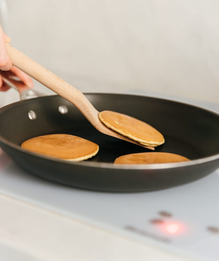 La Palette Coudée de Casavida retournant des pancakes dans une poêle, spatule en bois de hêtre