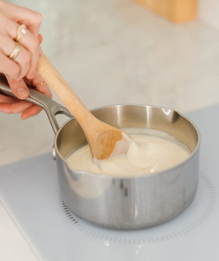 La Cuillère Fétiche de Casavida remuant une sauce dans une casserole en inox