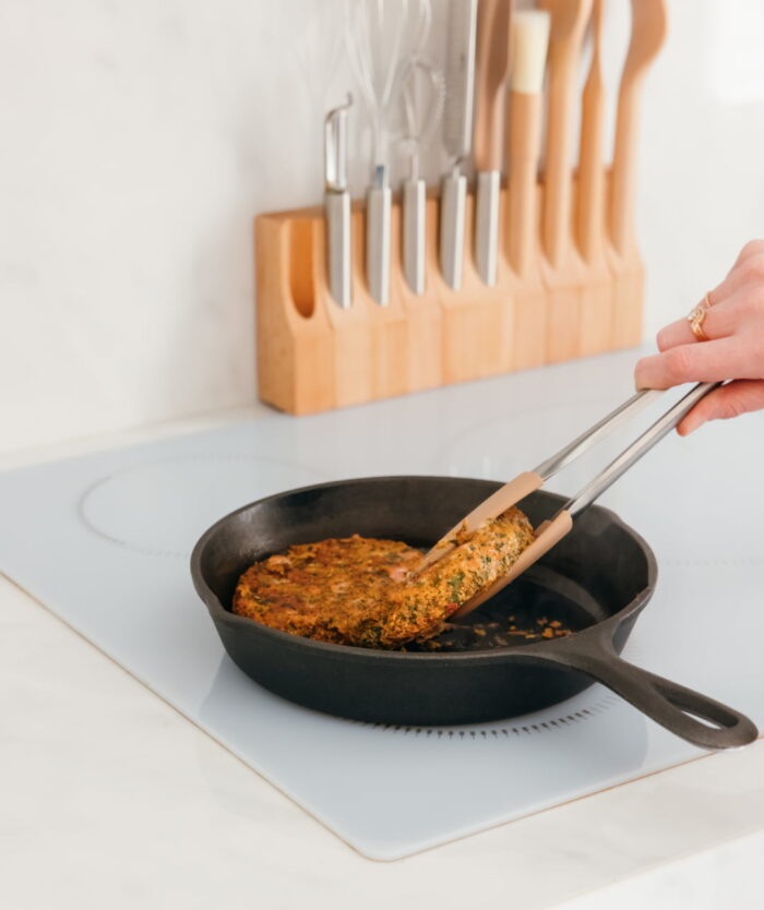 La Pince Agile de Casavida retournant une galette dans une poêle, pince de cuisine en inox et silicone