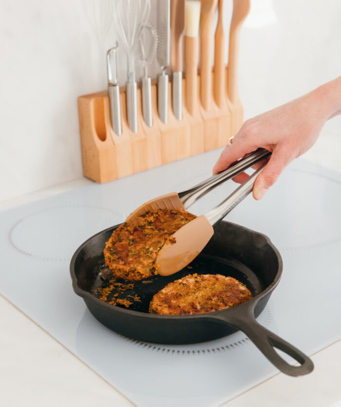 La Pince Agile de Casavida retournant une galette dans une poêle en fonte, pince de cuisine en inox et silicone