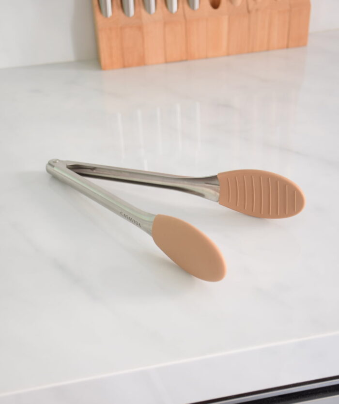 La Pince Agile de Casavida ouverte sur un plan de travail, pince de cuisine en inox et silicone platinium